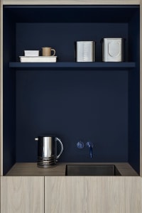 A modern kitchenette featuring metal shelves and a sink with a water dispenser.