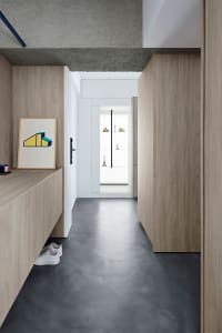 Modern minimalist entryway with concrete flooring and wooden cabinets.