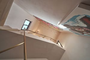 A staircase with a metal handrail and concrete steps set against white walls.
