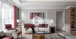 Modern minimalist living room with white walls, red accents, and black and white artwork.