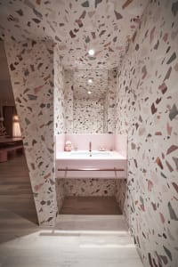 Modern minimalist bathroom with a patterned terrazzo floor and pink sink.