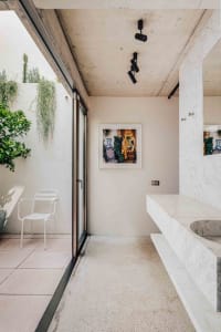 Modern minimalist bathroom with marble countertops and concrete floor.