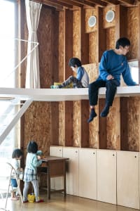 A modern residential space featuring wood OSB walls and a lofted sleeping area.