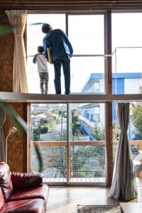 Two people looking out of a large window with wooden bars in a modern residential space.