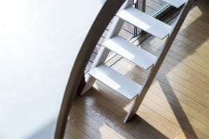 A modern steel staircase with white steps illuminated by sunlight.