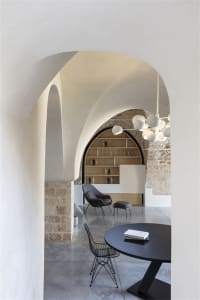 A modern living room with concrete and stone accents, featuring minimalist furniture and a circular table.