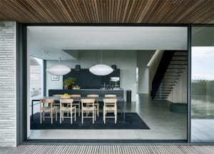 Modern minimalist kitchen with concrete finishes and a long dining table.