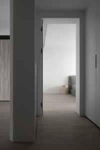 Modern minimalist bedroom with white walls and wooden floor.