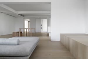 Modern minimalist living room featuring wood furniture, fabric cushions, and concrete elements.