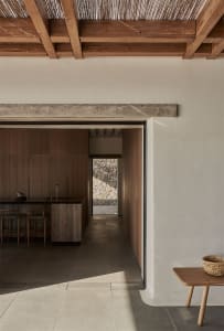 Modern minimalist kitchen with wooden finishes and a sleek black countertop.