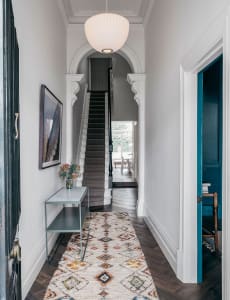 An entrance hall featuring a hardwood floor, a geometric rug, and a modern design aesthetic.