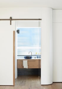 Modern bathroom with wood vanity, black vessel sink, and frosted glass window