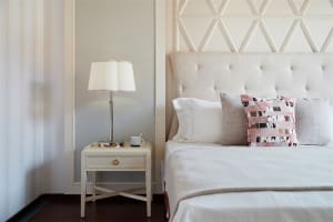 A cozy, modern bedroom featuring a white upholstered bed with a textured tufted headboard, set against a soft, patterned tile
