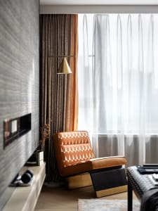 Modern interior design featuring a patterned couch, floor lamp, and fabric curtains in a living room.