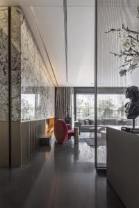 A modern living room featuring marble walls, a glass fireplace, and metallic accents.