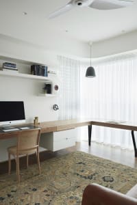A minimalist home office featuring a wooden desk, leather armchair, and patterned rug.