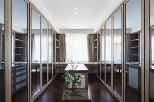 A modern wardrobe with glass doors and dark wooden flooring, featuring sleek lines and minimal design.