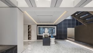 A minimalist lobby featuring black-and-white tiled flooring and a terrazzo table with sculptures and art.