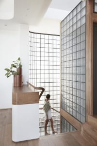 Person walking down a modern staircase featuring glass blocks and a white frame.
