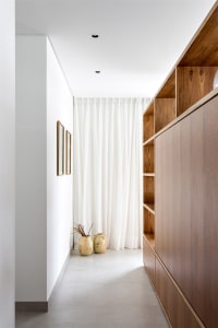 Modern minimalist interior with wooden shelves, white curtains, and concrete flooring.
