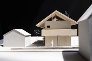 A minimalist modular house model made of light-colored wood.