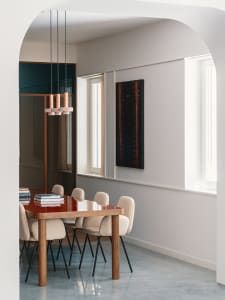 Modern dining room with a wooden table, beige chairs, and a hanging light fixture.