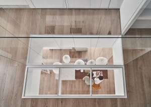 A modern kitchen with glass walls and a wooden floor