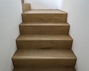 Modern, wooden staircase with light-colored wood panels.
