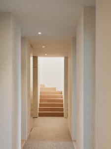 A modern minimalist interior with wooden stairs and white walls.