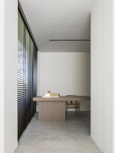 A minimalist home office with concrete flooring, a wooden desk, and a chair.