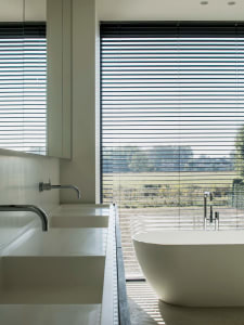 Modern bathroom with white concrete walls and floor, featuring a minimalist bathtub and sleek, contemporary fixtures.