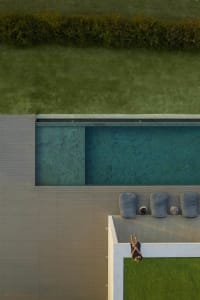 A modern swimming pool deck featuring wood and concrete materials.