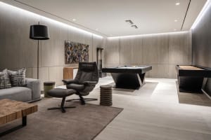 Modern living room featuring a contemporary leather recliner chair, wooden coffee table, and a sleek black pool table with bi
