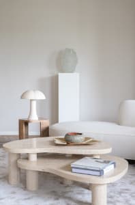 A modern minimalist living room featuring a sleek marble coffee table with rounded edges, placed on a soft neutral carpet.