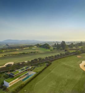 Modern residential home with a green roof and rooftop garden overlooking a golf course and countryside.