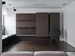 Modern minimalist living room with dark wood shelving, concrete floor, and leather sofa.