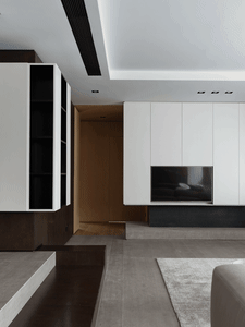 Modern living room featuring sleek, minimalist white cabinetry and gray concrete flooring.