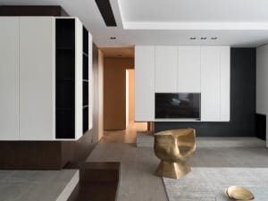 A minimalist living room with a combination of metal, glass, concrete, and tile materials, featuring a distinctive gold chair