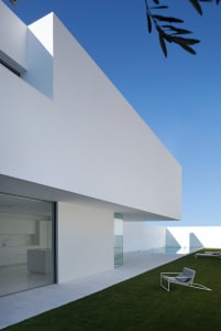 Modern, minimalist exterior of a white concrete house with a clean, angular design.