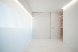 Empty white minimalist room with closed doors and sleek lines.