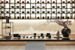 A modern tea room features a wall display of ceramic teapots and vases arranged in a grid pattern, enhancing the aesthetic an