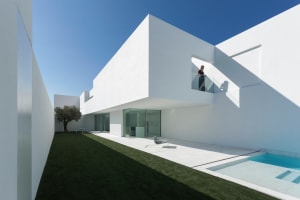 A modern white concrete house with large glass walls.