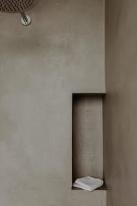 A modern bathroom with a sleek, minimalist design featuring a concrete shower wall and built-in storage niche.