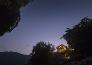 A modern concrete home nestled in the natural landscape at dusk.
