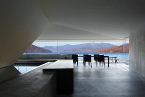 A modern interior featuring concrete walls and glass windows overlooking a scenic landscape.