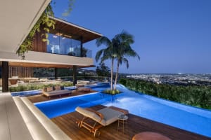A modern residential pool deck featuring wood, concrete, and lighting elements.