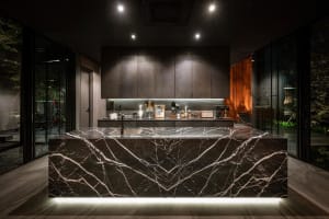 Modern kitchen interior featuring a large marble island with a sink and various kitchen appliances and decor.