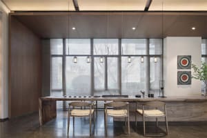 A modern restaurant with wooden tables, chairs, and bamboo lighting hanging from the ceiling.
