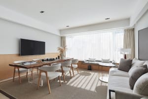 A modern minimalist living room with a large window, white furniture, and wooden accents.