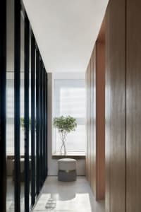 Modern interior design featuring a glass corridor with white flooring and a potted plant.